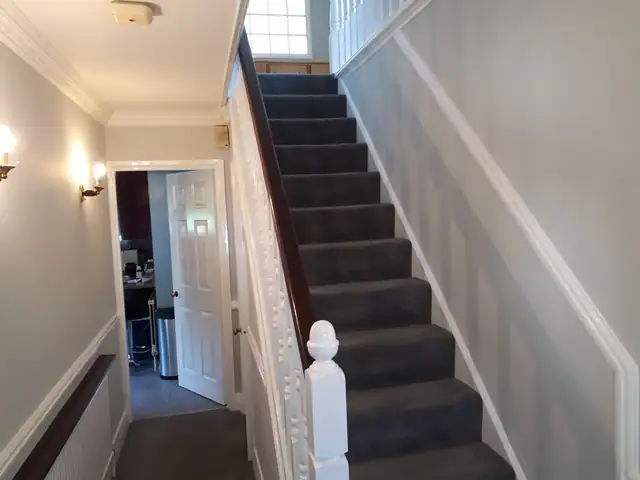 Hallway and stairs with pale grey walls, white panelling and wall lights